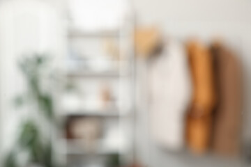 Shelving unit and rack with clothes in interior of dressing room. Blurred view