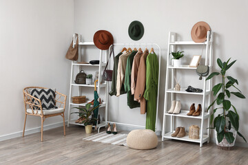 Rack with clothes, shelving unit and chair in interior of dressing room