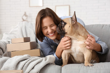 Pretty young woman with French bulldog and parcels at home