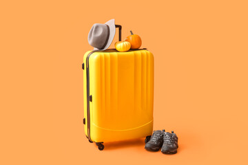 Beautiful autumn composition with suitcase, hat, shoes and pumpkins on orange background