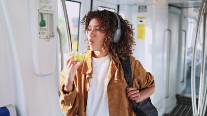 Young latin woman enjoying a green apple while commuting on public transportation during her daily routine