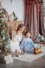 Smiling girl with mom near christmas tree at home