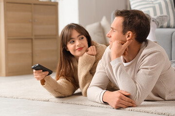 Young couple watching TV on floor at home