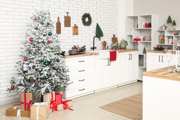 Interior of light kitchen with counters, Christmas tree and presents