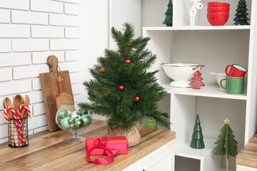 Small Christmas tree with gift box on counter in kitchen