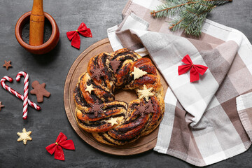Composition with tasty Christmas pastry wreath, napkin, decorations and poppy seeds on dark background
