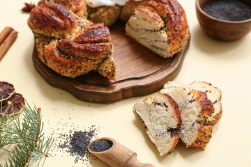 Wooden board with tasty Christmas pastry wreath and poppy seeds on color background