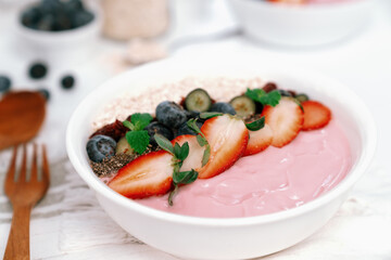 Presented by fruits putting yogurt toppings with strawberry, berry, oats, raisins and chia seed decorated by peppermint in white blow. Pink background. Set of healthy dairy product choice. Pecuniary.