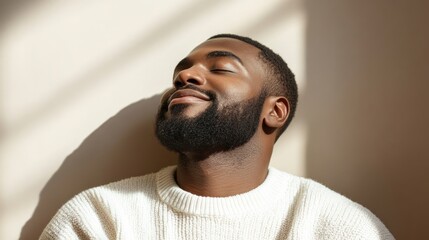A man relaxes in warm sunlight, smiling gently as he enjoys a peaceful moment in a cozy space