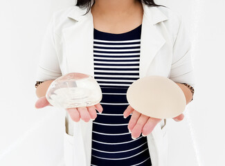 Silicone breast implants surgery, Doctor holding smooth and rough breast prostheses with both...