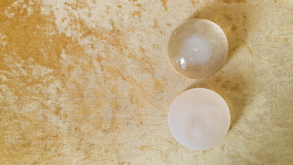 Silicone breast implants surgery, top view of two silicone breast augmentation on golden sofa background, medical equipment in clinic or hospital.