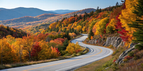 Naklejka premium winding mountain road surrounded by vibrant autumn foliage under a clear blue sky