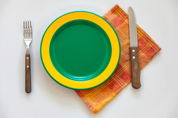 Empty plate isolated on white background with rustic cutlery set next to it