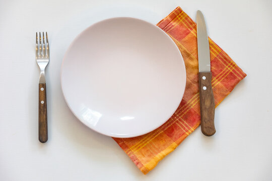 Empty plate isolated on white background with rustic cutlery set next to it