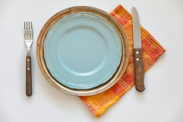 Empty plate isolated on white background with rustic cutlery set next to it