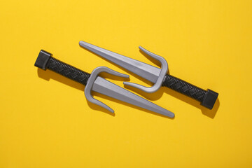 Toy plastic sai weapons on yellow background
