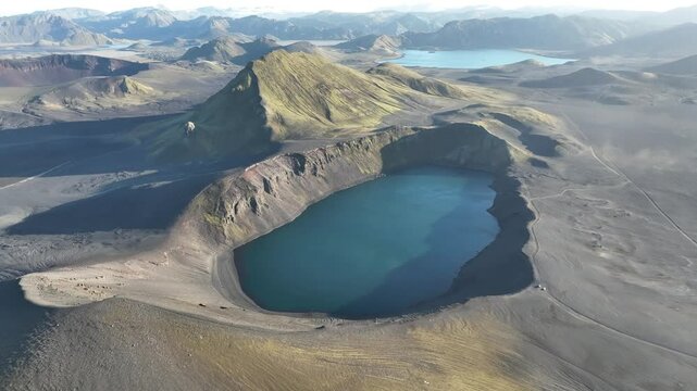 Cinematic aerial video of incredible Icelandic highlands with mountains, volcanic lakes and river on a sunny day