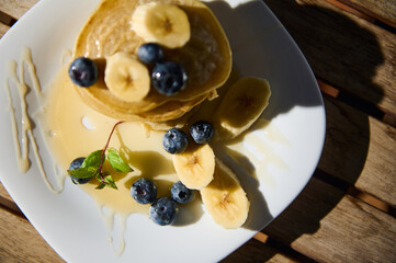 Delicious pancakes topped with bananas and blueberries on a sunny morning