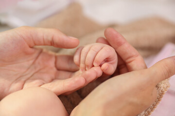 Mother's hand holds the newborn's hand. Mother's love and care.