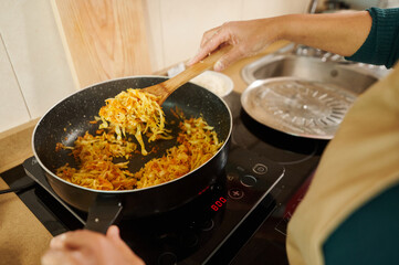 Person cooking stir-fried vegetables in a modern kitchen setting