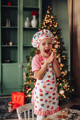 a girl child in the kitchen with a Christmas tree is preparing or cooking ginger cookies for Christmas or New year