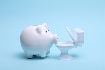 Ceramic white piggy bank with toilet on a blue background. Business concept. Conceptual photo