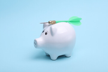 Ceramic white piggy bank with darts on a blue background. Business concept. Conceptual photo