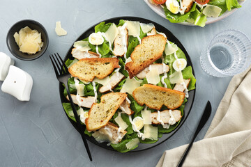 Delicious Caesar salad with chicken served on grey textured table, flat lay