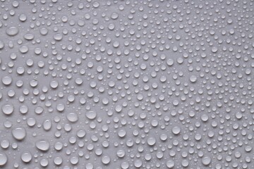 Water drops on gray background, top view