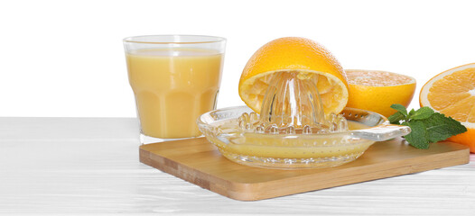 Glass juicer and fresh oranges on wooden table against white background