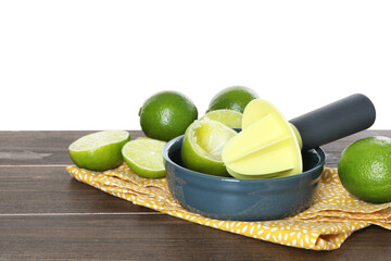 Plastic juicer and fresh limes on wooden table against white background