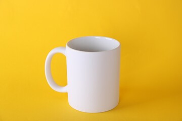 One blank white mug on yellow background. Mockup for design