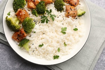 Tasty rice with broccoli, chicken and parsley on grey table, top view