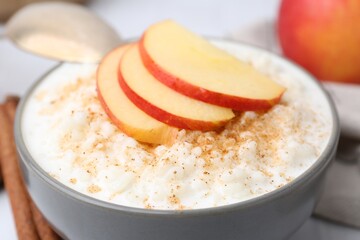 Delicious rice pudding with apples and cinnamon on white table, closeup