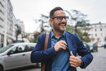 handsome businessman put the phone in pocket in front company