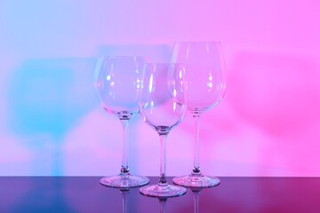 Empty glasses on table against color background