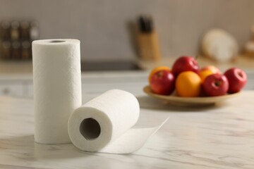 Rolls of paper towels and fruits on white marble table in kitchen