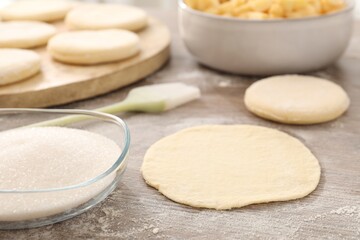 Making pirozhki (stuffed pastry pies). Pieces of dough on wooden table, closeup