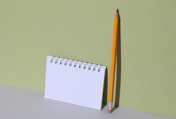 Stationery pencil with notebook on a green background