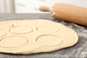 Making pirozhki (stuffed pastry pies). Raw dough and rolling pin on gray table, closeup