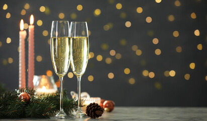 Delicious champagne in glasses and Christmas decor on marble table against blurred lights, closeup. Space for text