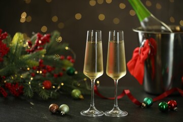 Delicious champagne in glasses and Christmas decor on grey table against blurred lights, space for text