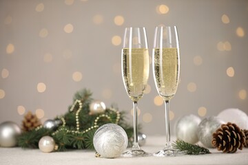 Delicious champagne in glasses and Christmas decor on white table against blurred lights