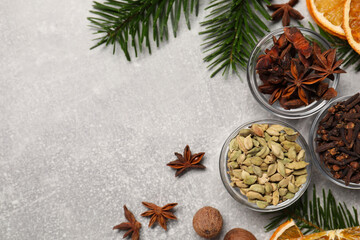 Different spices, dried orange slices and fir tree branches on light grey table, flat lay with space for text. Christmas season