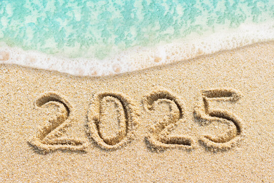 new year 2025 concept photo. Handwritten numbers on the sandy beach with blue ocean wave 