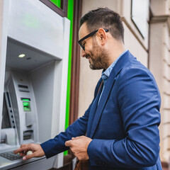 Adult caucasian man stand and hold credit card use cash machine