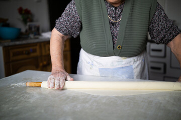 close up of grandmother rolling dough with a rolling pin. Elderly woman rolling out dough with a rolling pin