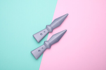 Toy ninja throwing knives on blue pink background