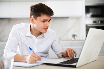 Young man getting knowledge using internet and laptop at home