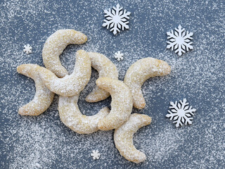 Vanilla rolls with walnuts - delicious Christmas cookies, homemade baking. White snowflakes around